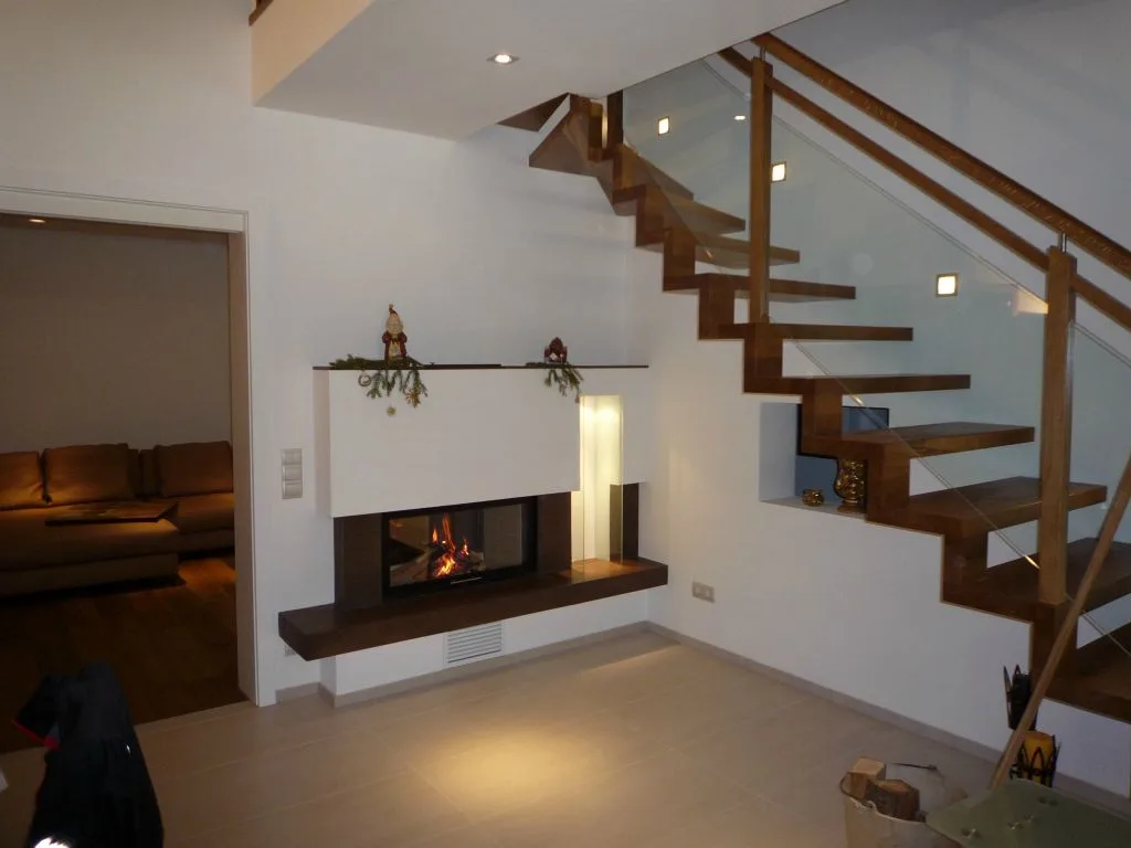 Ofen mit Sichtfenster unter einer offenen Holztreppe