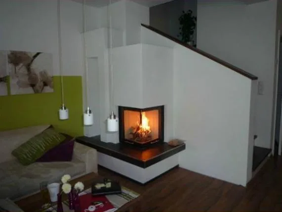 Weißer Eckofen mit brennendem Feuer und dunkler Sitzbank