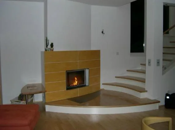 Ofen mit heller Holzverkleidung an einer geschwungenen Treppe